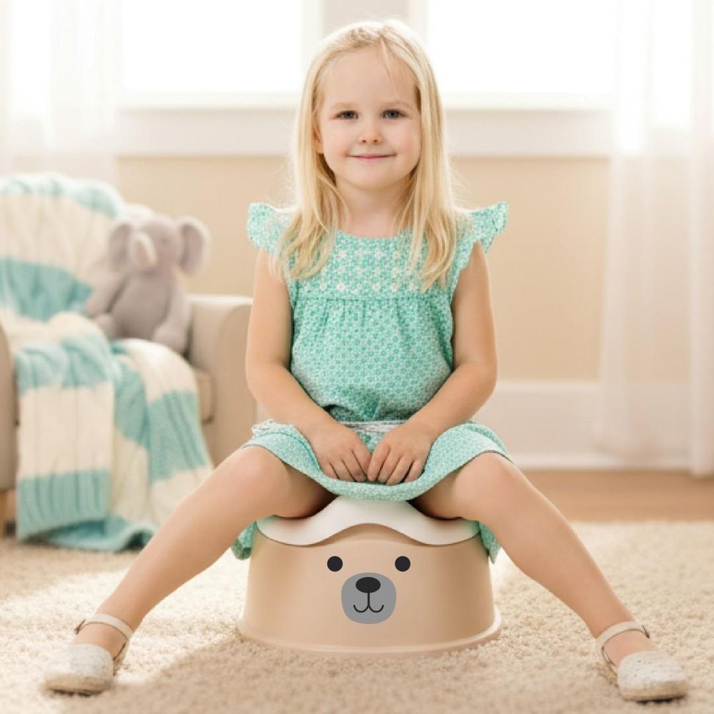 Petite fille assise sur le pot bébé SUN BABY dans une chambre d'enfant.
