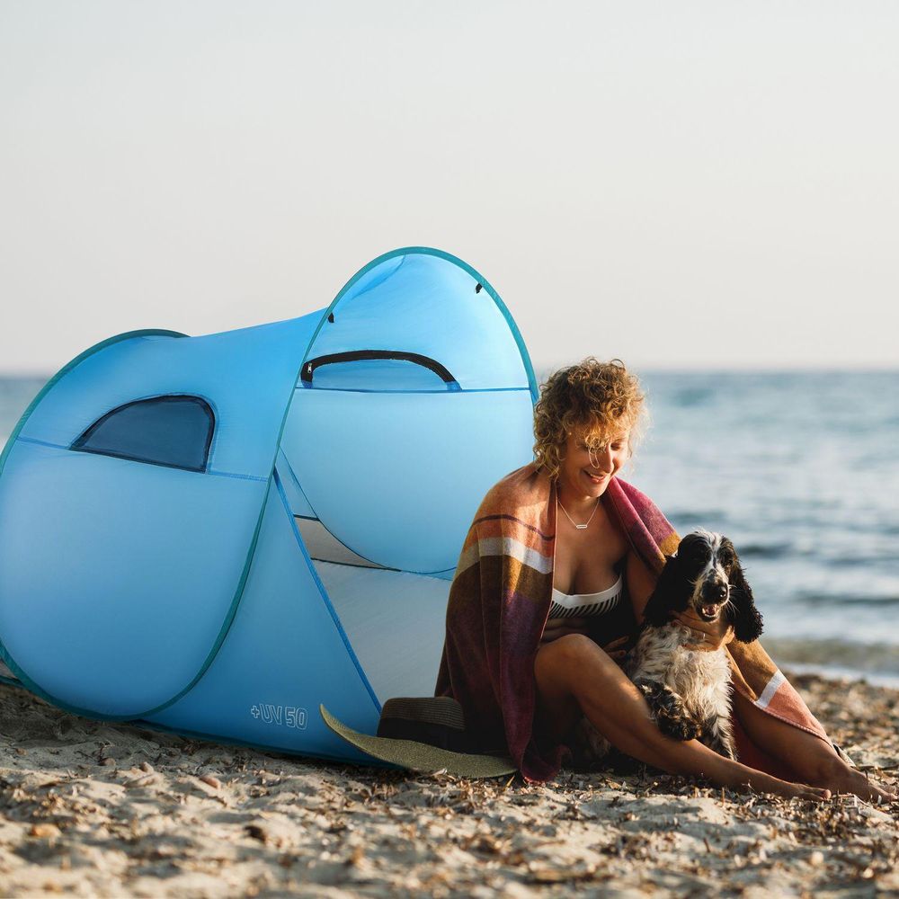 Frau mit Hund entspannt im UV50+ Strandzelt am Meer