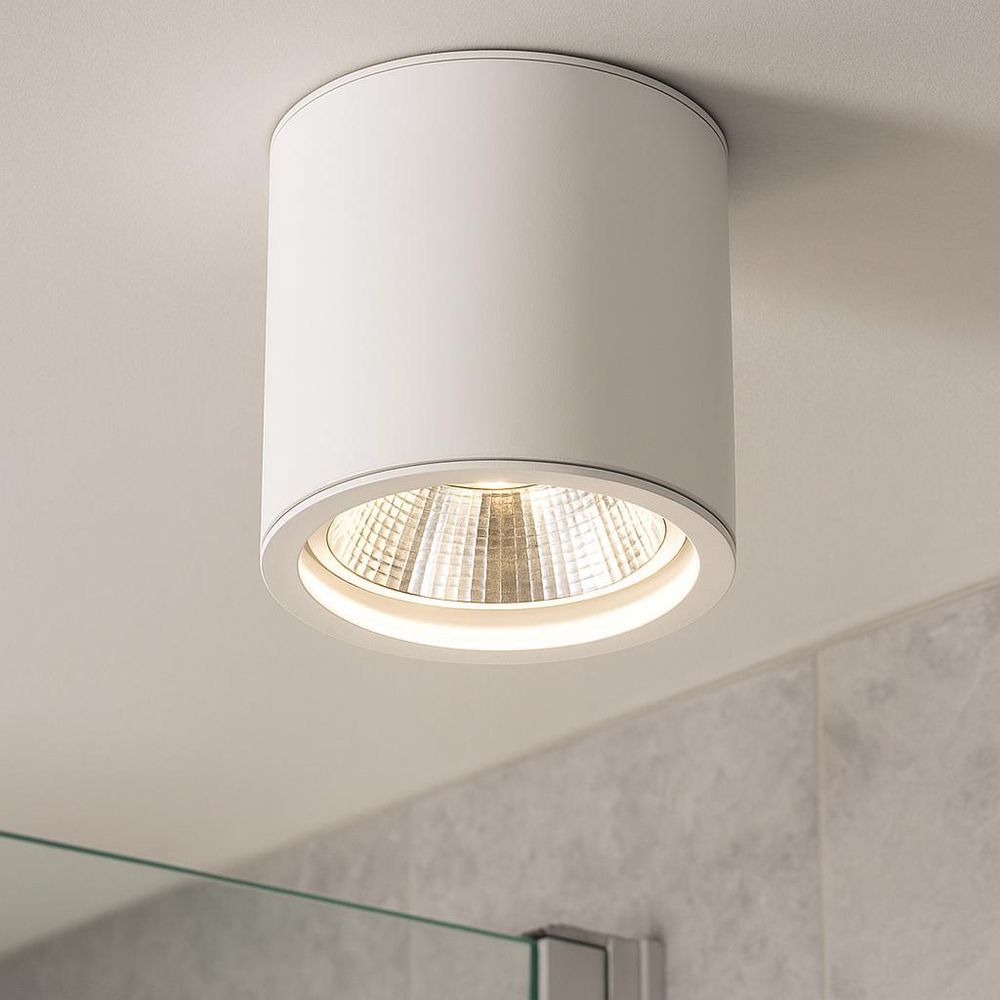 Moderne weiße Deckenleuchte mit rundem, schwenkbarem Spot in minimalistischem Wohnraum.
