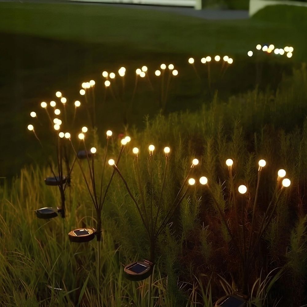 Helles Licht von kugelförmigen Gartenleuchten, das einen Pfad im Gras bildet.
