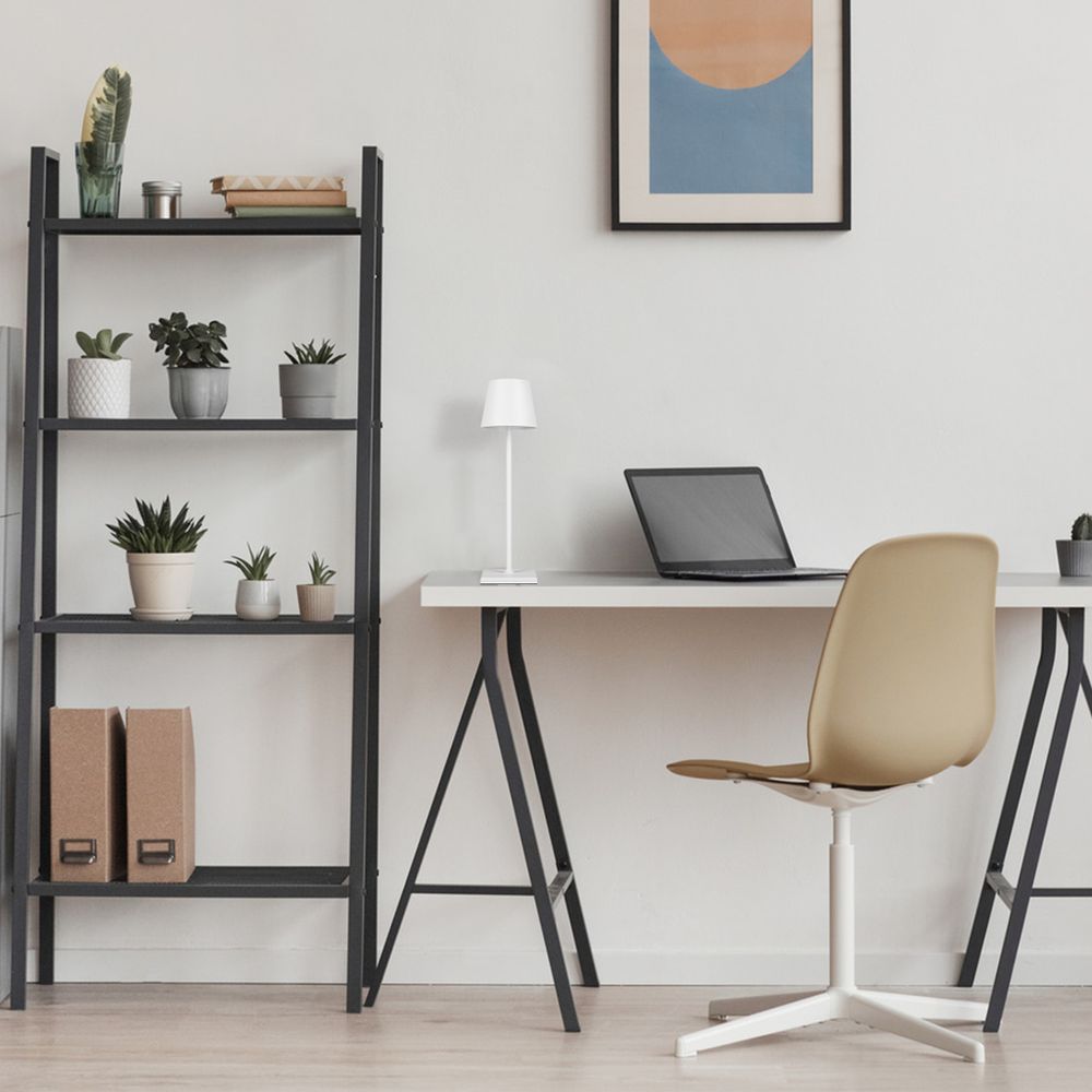 Lampe auf dem Schreibtisch im Zimmer, neben Laptop und Stuhl, minimalistische Einrichtung.