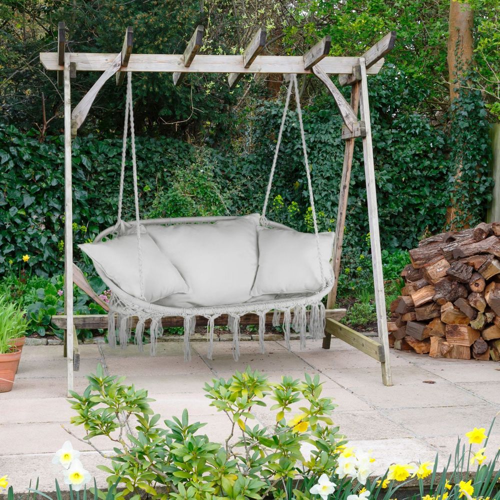 Grauer Hängesessel mit Kissen hängt an einem Holzgestell im Garten.