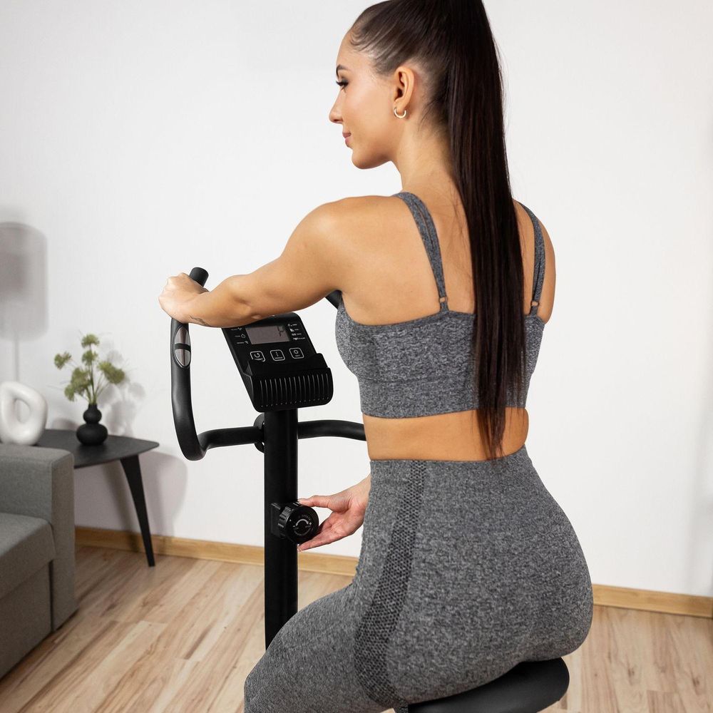 Nahaufnahme einer jungen Frau auf dem Heimtrainer, die den Widerstandsknopf am Lenker einstellt