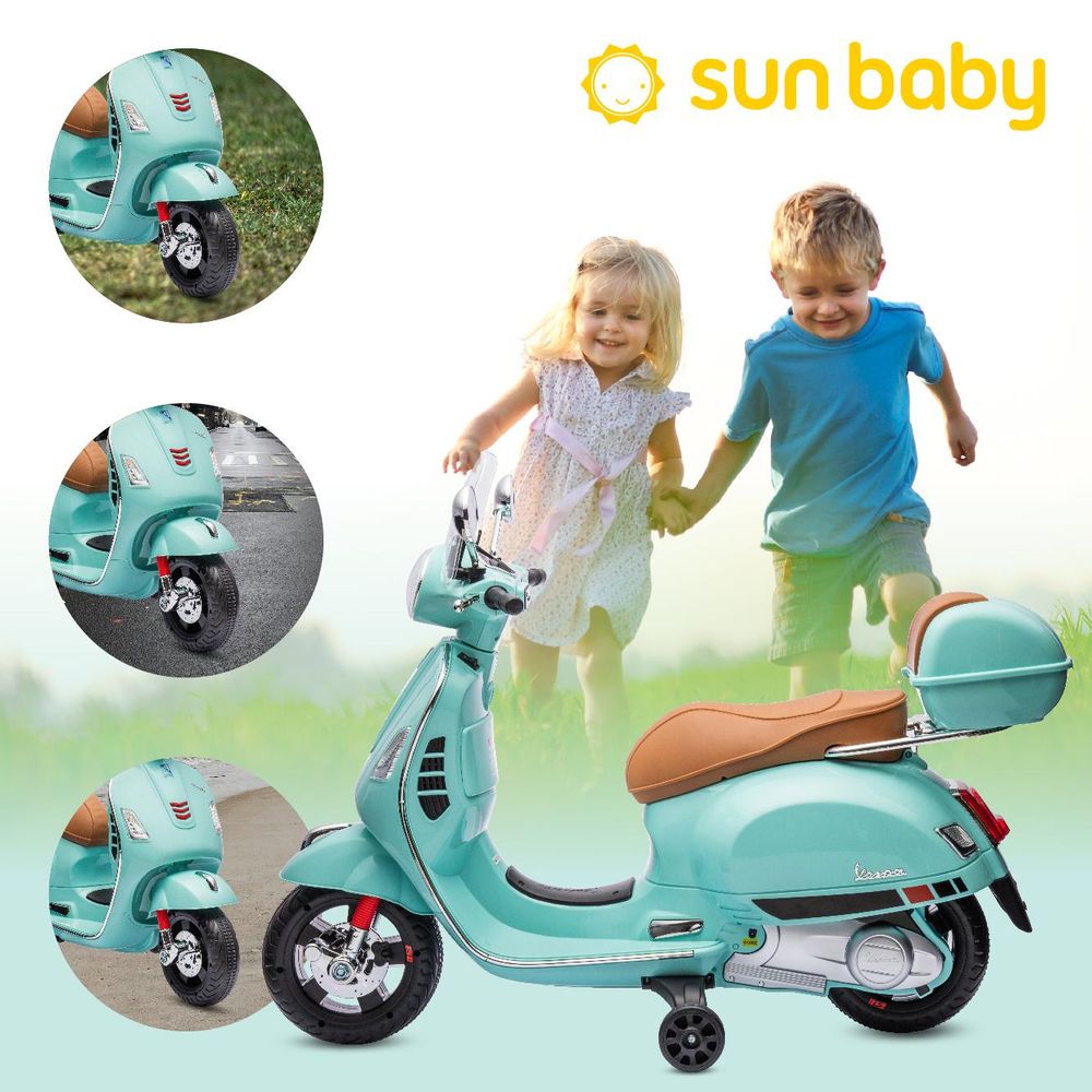 Skuter Vespa Sun Baby na trawie, dzieci biegną obok, widoczne koła i detale.