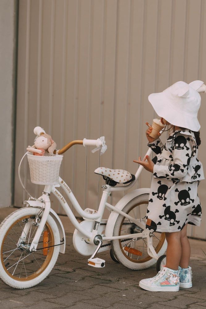 Bambina accanto alla bicicletta, pronta per una passeggiata all'aperto.