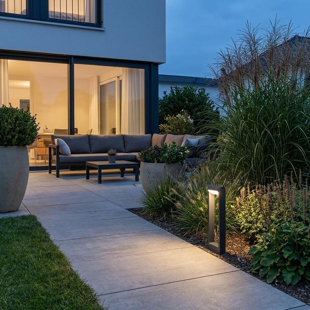 Graue Gartenlampe beleuchtet Steinweg bei Nacht.