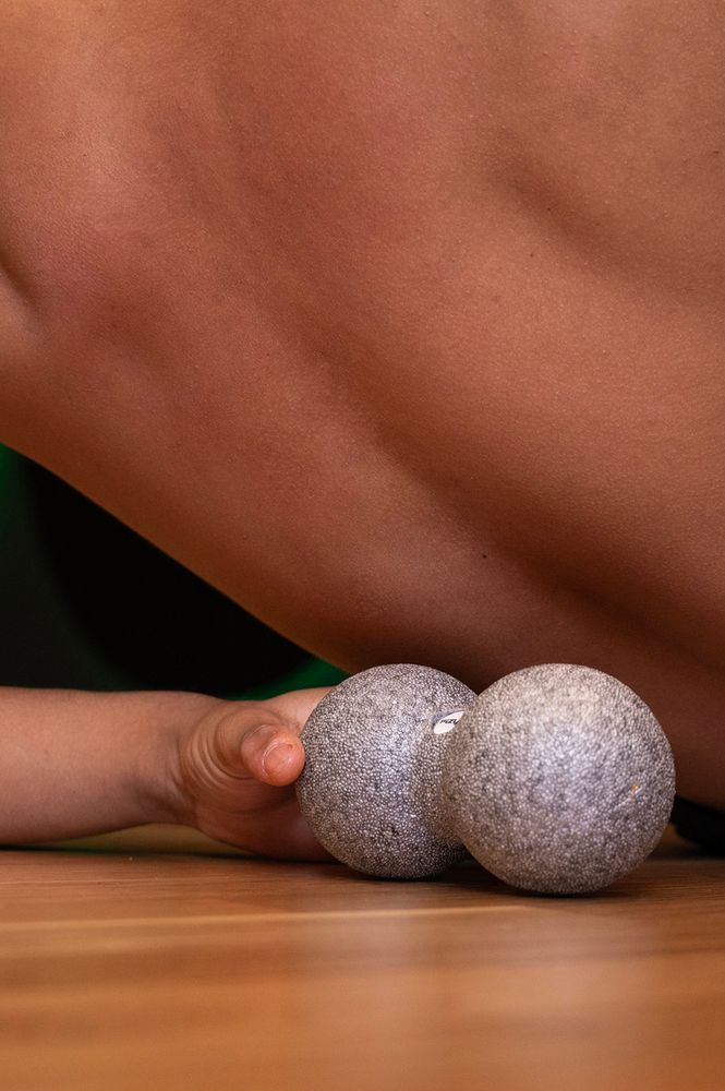 Osoba ćwicząca i wykorzystująca piłkę do masażu duoball FIZYO 16x8 cm
