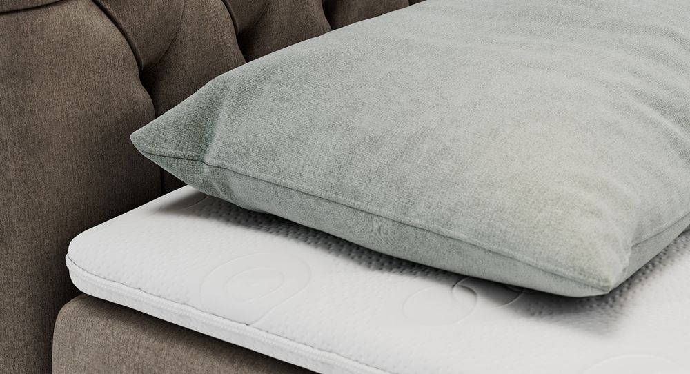 Gestepptes Kopfteil eines braun Bettes. Eine Topper-Matratze liegt auf dem Bett