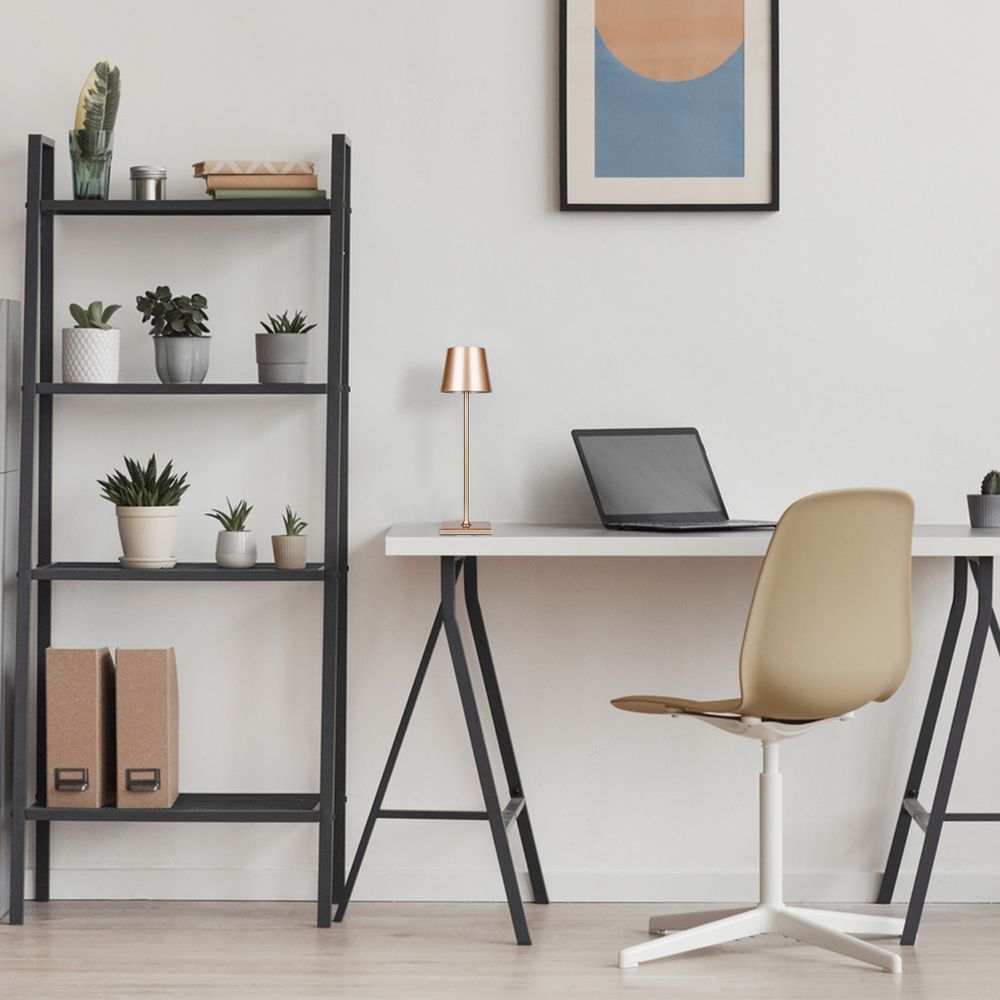 Lampe auf dem Schreibtisch im Zimmer, neben Laptop und Stuhl, minimalistische Einrichtung.