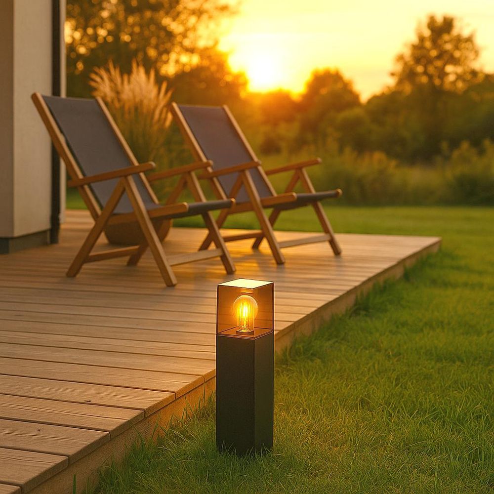 Moderne Außenleuchte mit Glas und sichtbarer Glühbirne auf Terrasse bei Sonnenuntergang platziert.