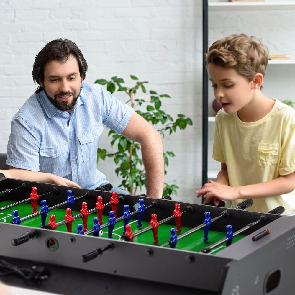 Vater und Sohn spielen Tischfußball zusammen zu Hause