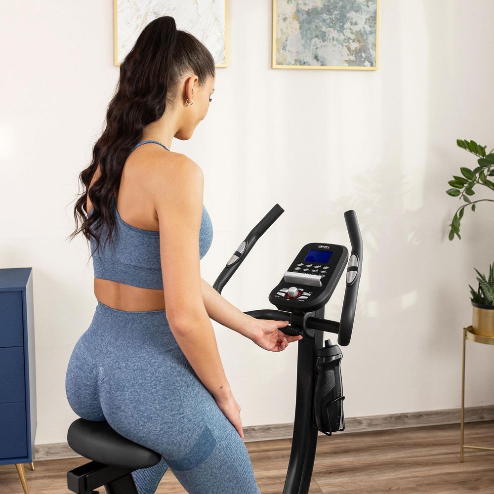 Frau trainiert auf Heimtrainer. Fitnesstraining zu Hause. Heimtrainer mit Flaschenhalter