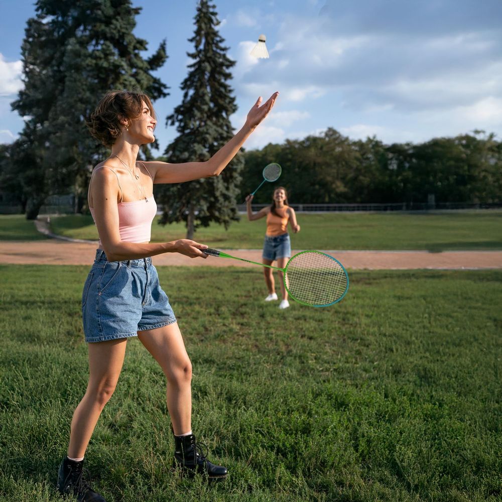 Zwei junge Frauen spielen Badminton im Park.