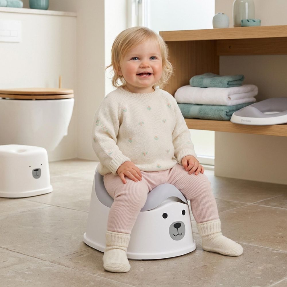 Niña sentada sola en el orinal gris con diseño de oso.