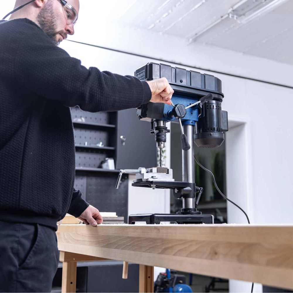 Das Bild zeigt eine Person bei der Arbeit mit der Tischbohrmaschine.