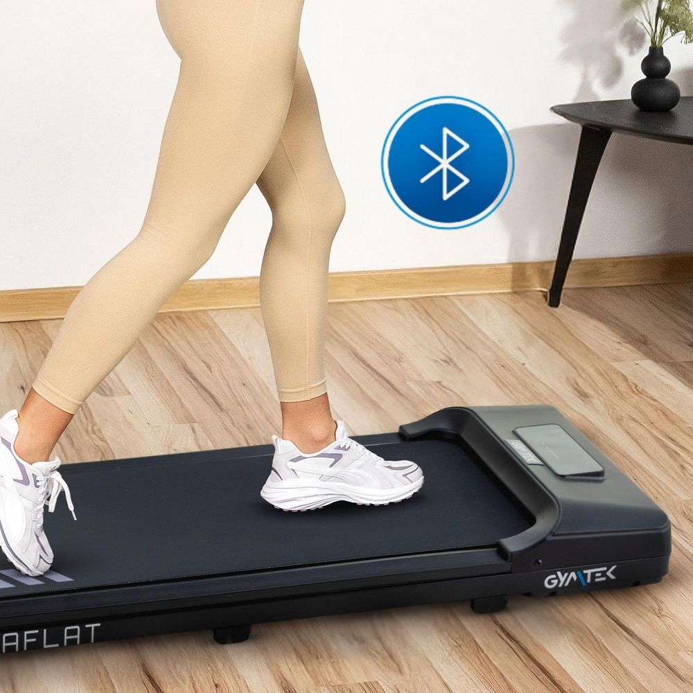 Person geht auf dem Laufband Gymtek; Bluetooth-Symbol; hellbeige Sportkleidung.