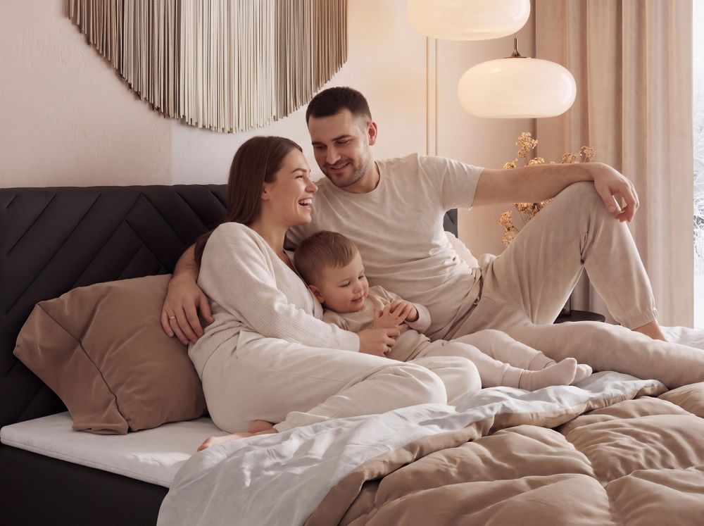 Gestepptes Kopfteil eines grau Bettes. Eine Topper-Matratze liegt auf dem Bett