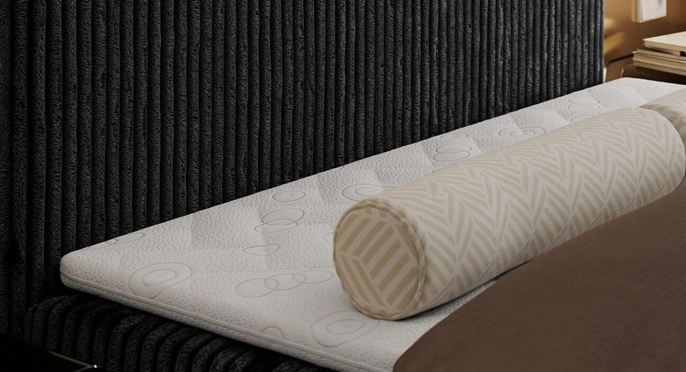 Kopfteils eines schwarzen Bettes aus Cordstoff. Eine Topper-Matratze liegt auf dem Bett