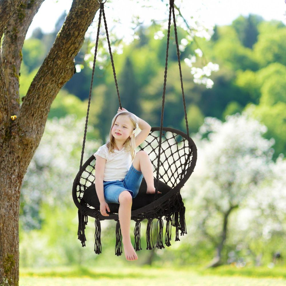Süßes blondes Mädchen sitzt und entspannt sich in einem Hängesessel im Garten