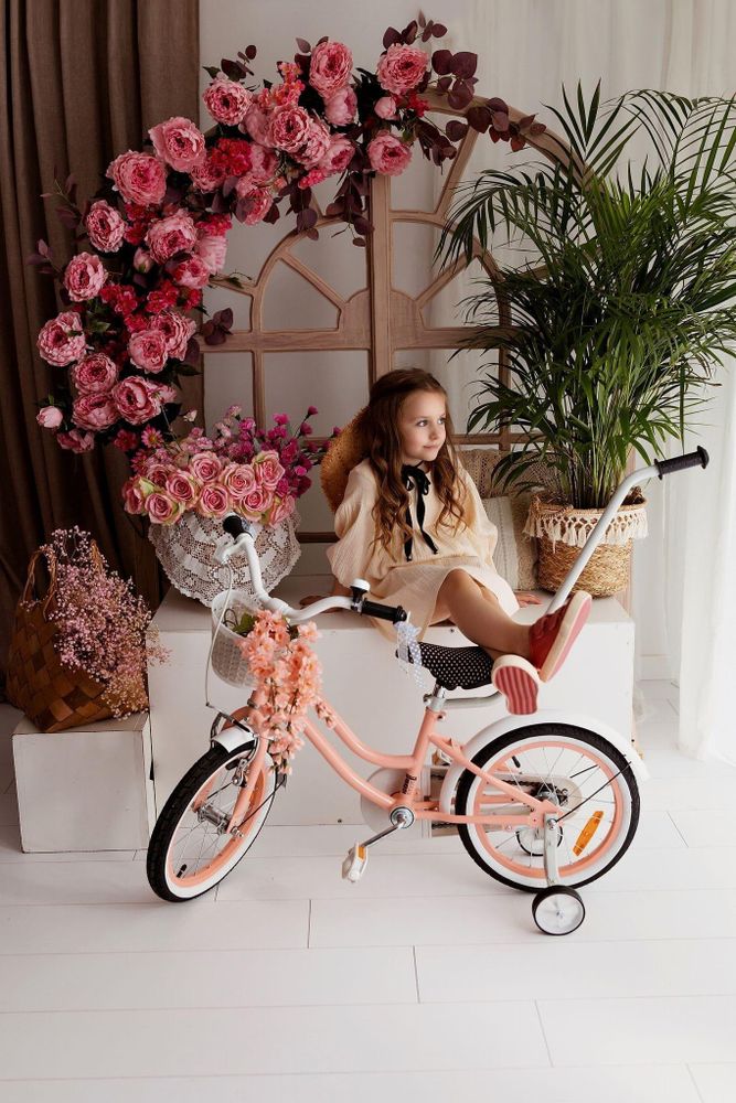 Mädchen sitzt auf dem Fahrrad in einem blumigen Raum