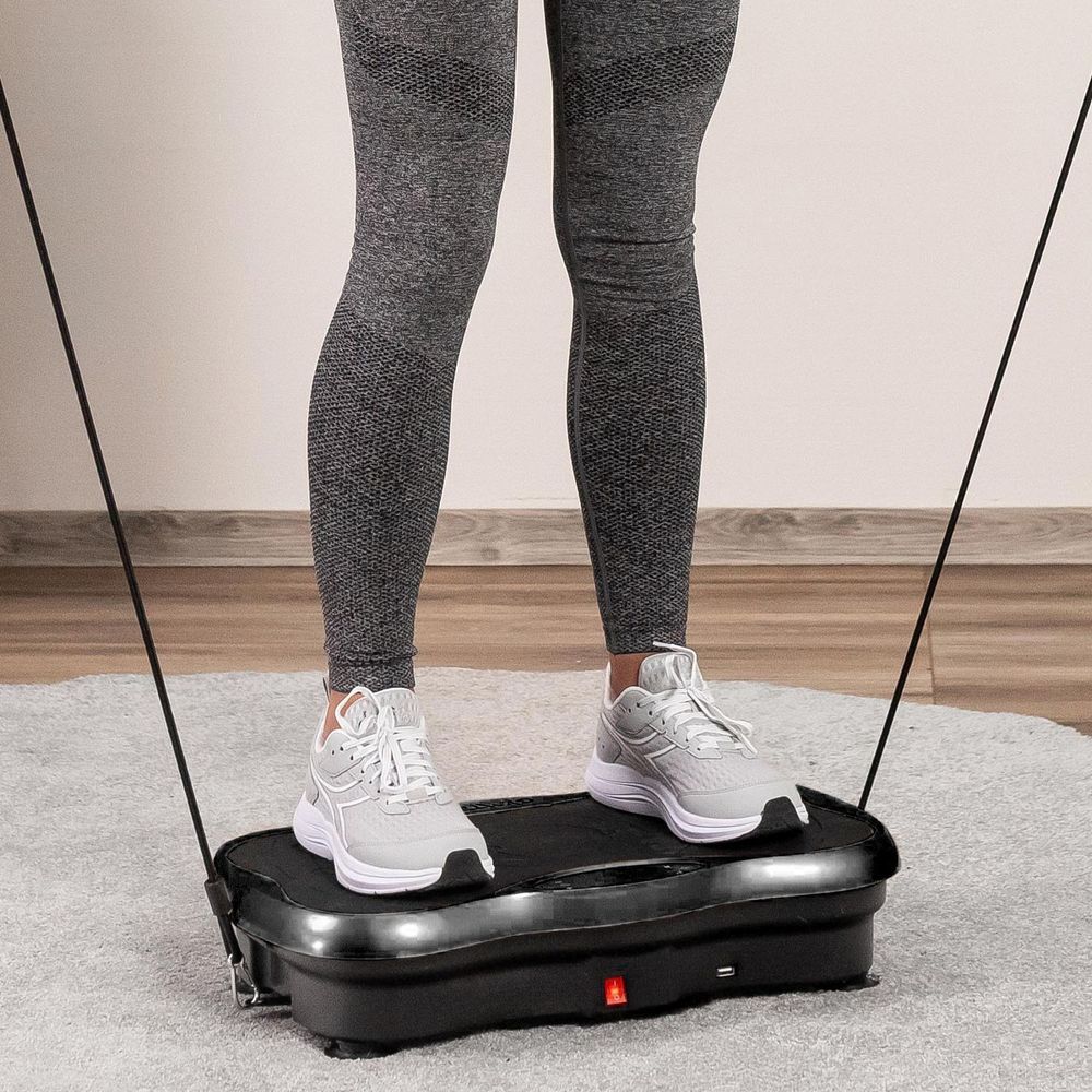 Beine einer Frau auf der Vibrationsplatte während des Trainings.
