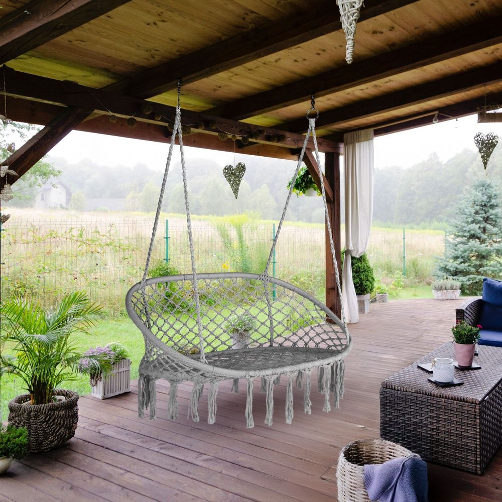 Überdachte Terrasse mit Hängeschaukel und Gartenblick.