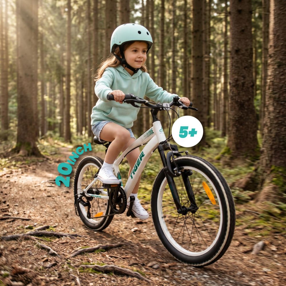 Niña montando la bicicleta SUN BABY Tiger Bike en un sendero forestal.