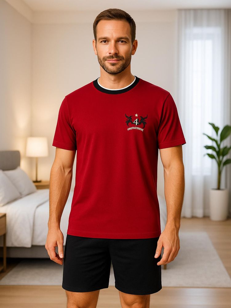 Mann trägt einen kurzen roten Herrenschlafanzug mit Motivdruck und schwarzer kurzer Hose