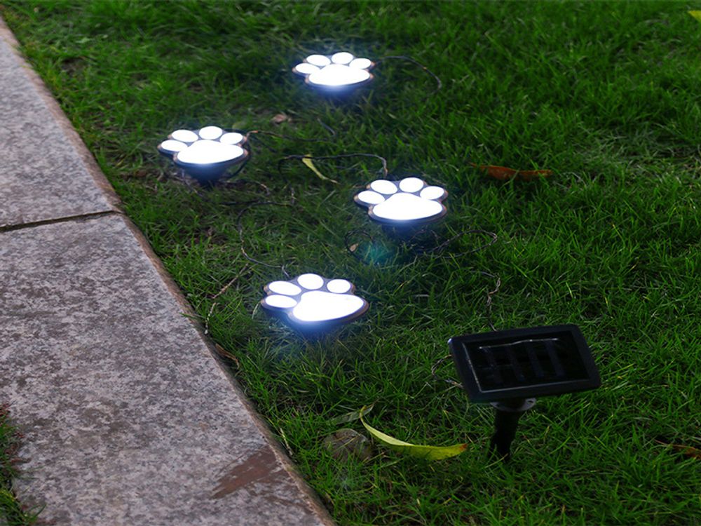 Solarbetriebene LED-Gartenleuchten in Pfotenform, beleuchten Rasen im Dunkeln. Solarpanel im Boden.