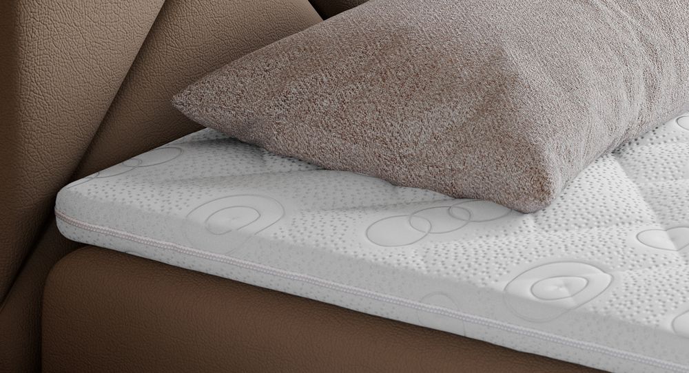 Gestepptes Kopfteil eines braun Bettes. Eine Topper-Matratze liegt auf dem Bett