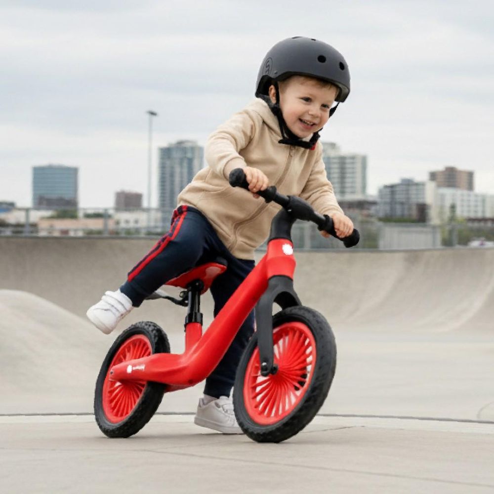 Dítě jedoucí na červeném odrážedle Sun Baby Sport ve skateparku.