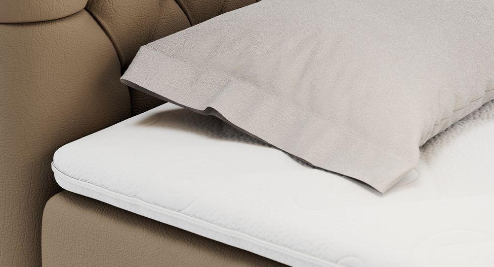 Gestepptes Kopfteil eines braun Bettes. Eine Topper-Matratze liegt auf dem Bett