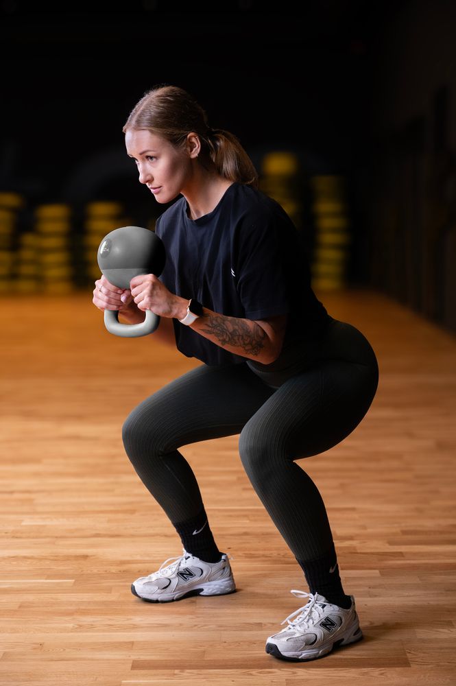Osoba ćwiczy przy pomocy ciężarka hantla miękki kettlebell FIZYO