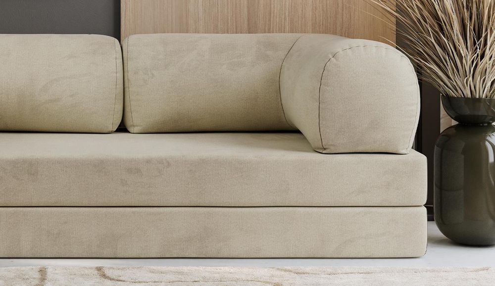 Detailansicht eines beigen Sofas mit runden Armlehnen und weichen Rückenkissen.