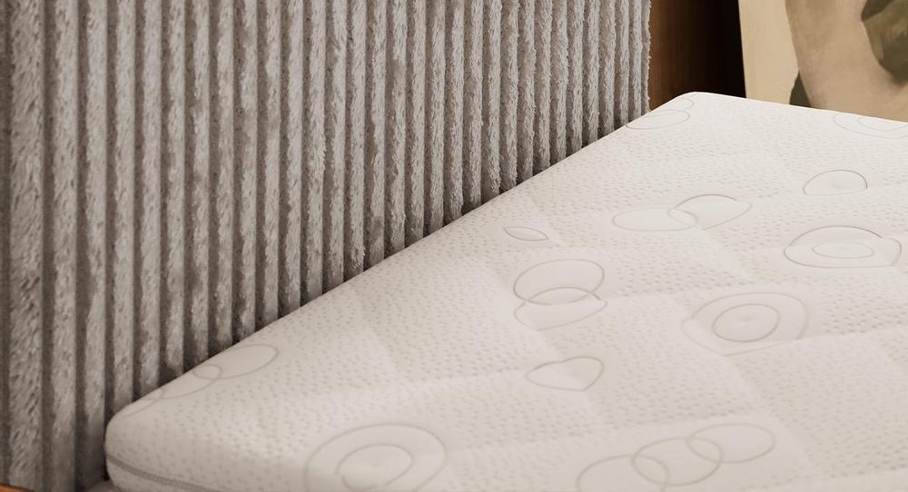 Kopfteils eines schwarzen Bettes aus Cordstoff. Eine Topper-Matratze liegt auf dem Bett