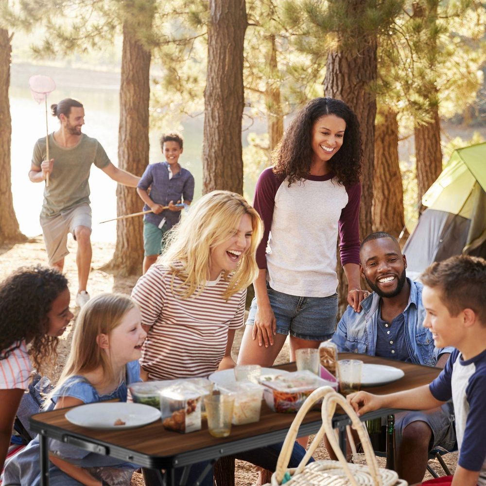 Fröhliche Familie beim Picknick an einem Campingtisch
