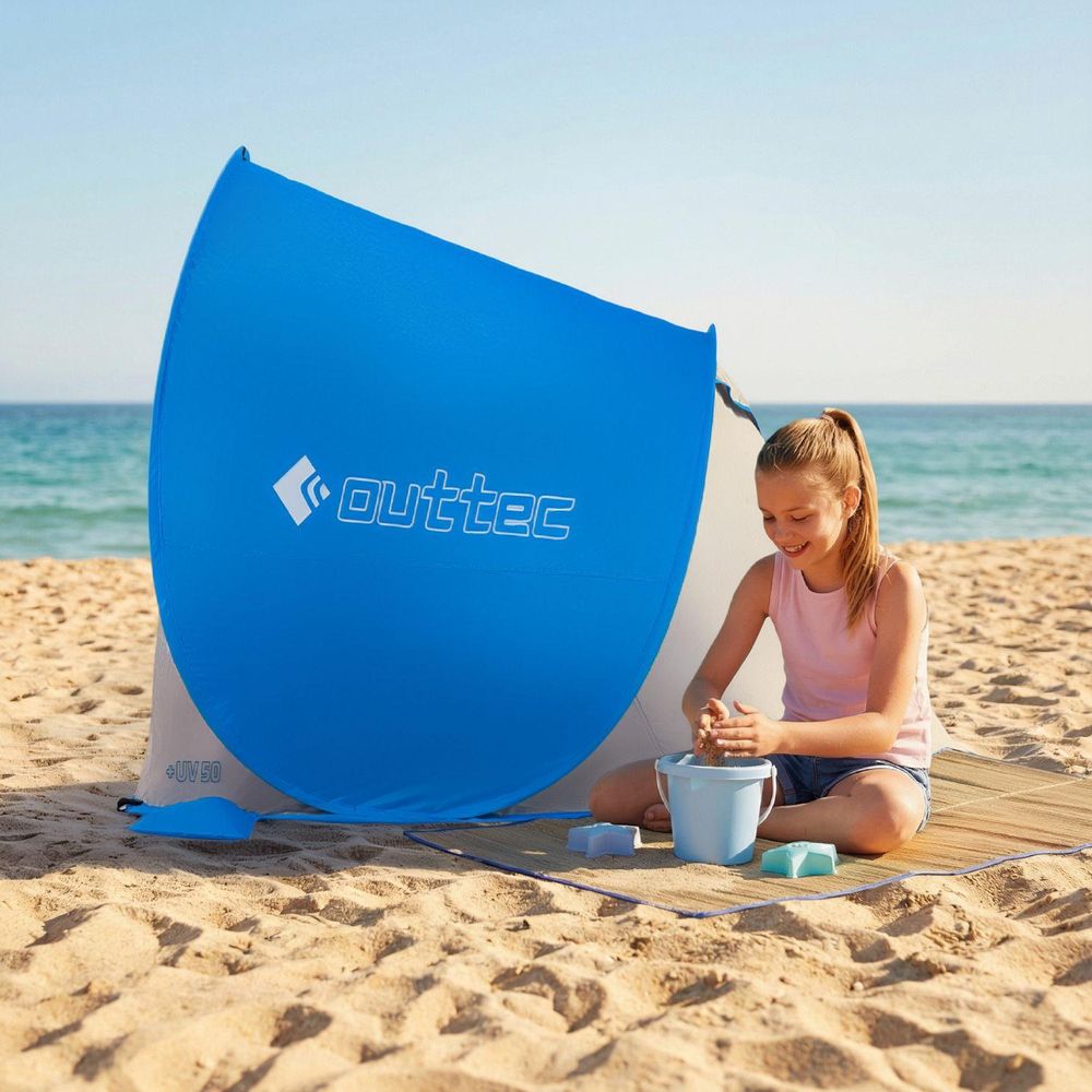 Kind spielt mit Sandspielzeug neben dem blauen Outtec Zelt am Strand