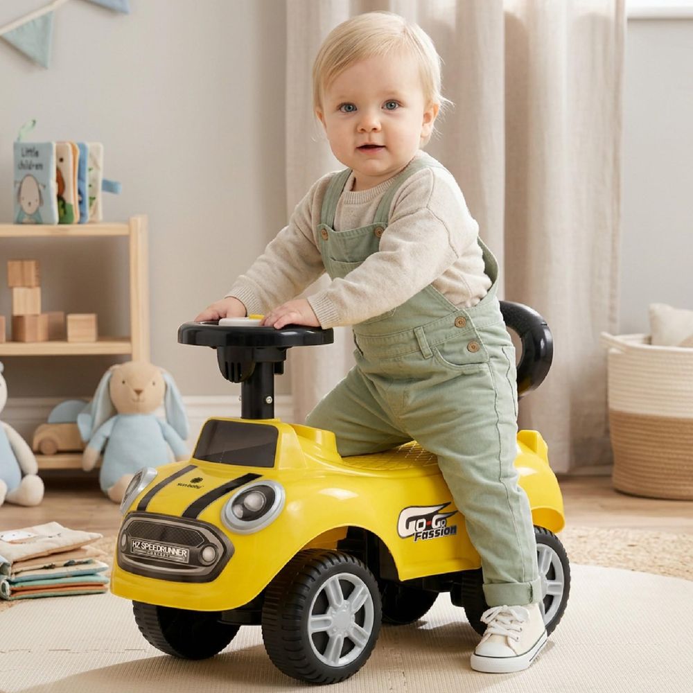 Kleinkind sitzt auf gelbem Rutschauto im Kinderzimmer