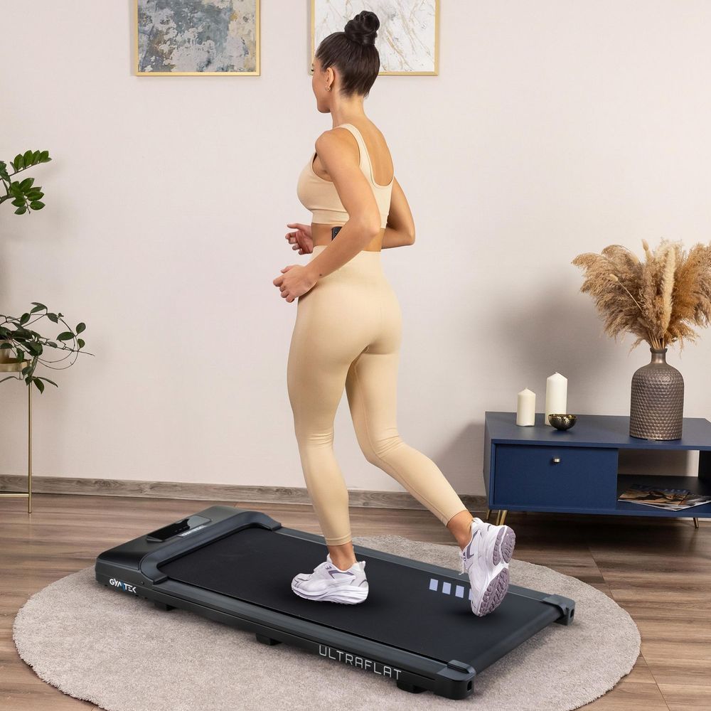 Frau trainiert auf einem ultraflachen Laufband zu Hause.