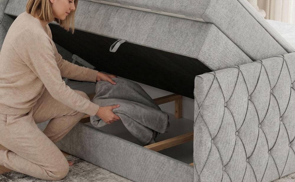 Eine Frau, die eine Decke in einen Behälter im Bett verstaut