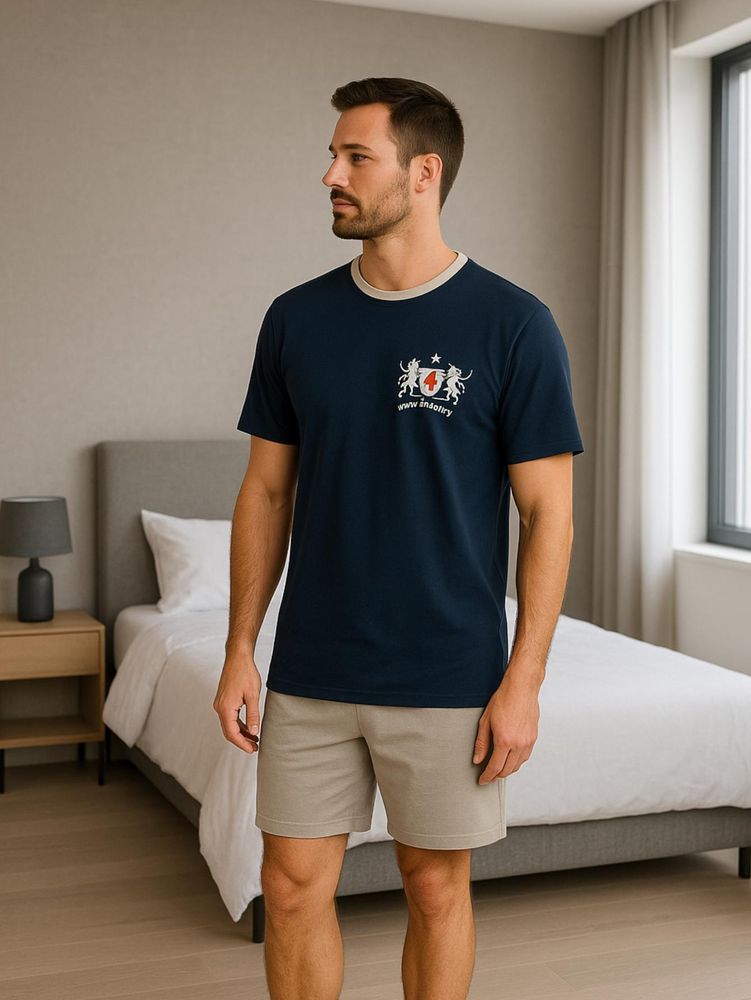 Das Bild zeigt einen Herren der einen kurzarm Schlafanzug mit blauem T-Shirt und grauer kurzer Hose