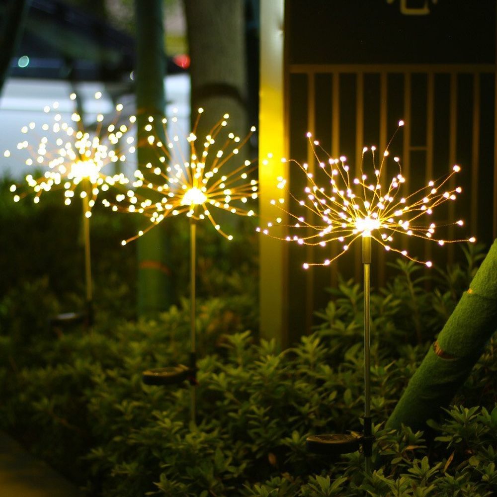 Dekorative Lampen mit Erdspieß sehen aus wie Glühwürmchen im Gras.