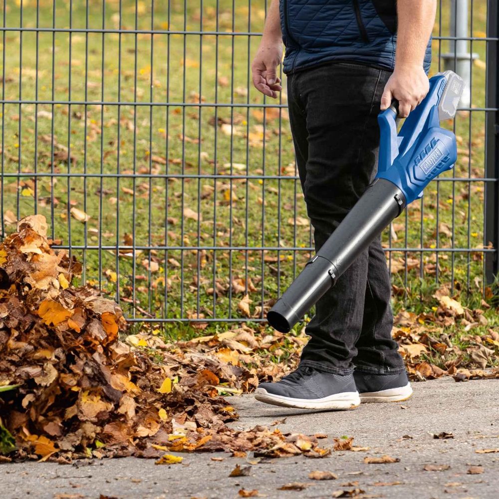 Das Bild zeigt eine Person beim Arbeiten mit dem Laubbläser.