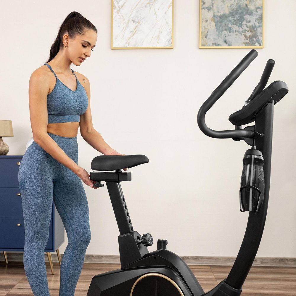 Frau passt den Sattel ihres Heimtrainers an. Ergonomischer Sitz