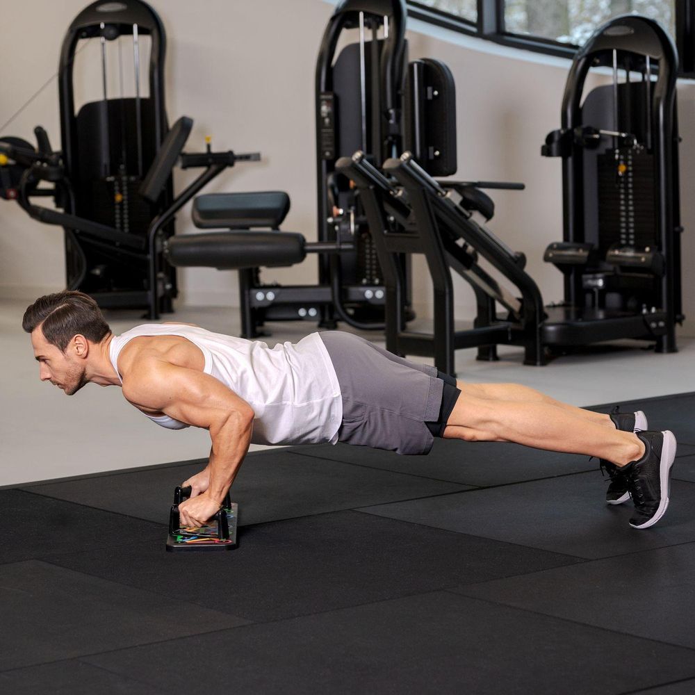 Mann macht Liegestütze mit Push-Up-Griffen im Fitnessstudio.