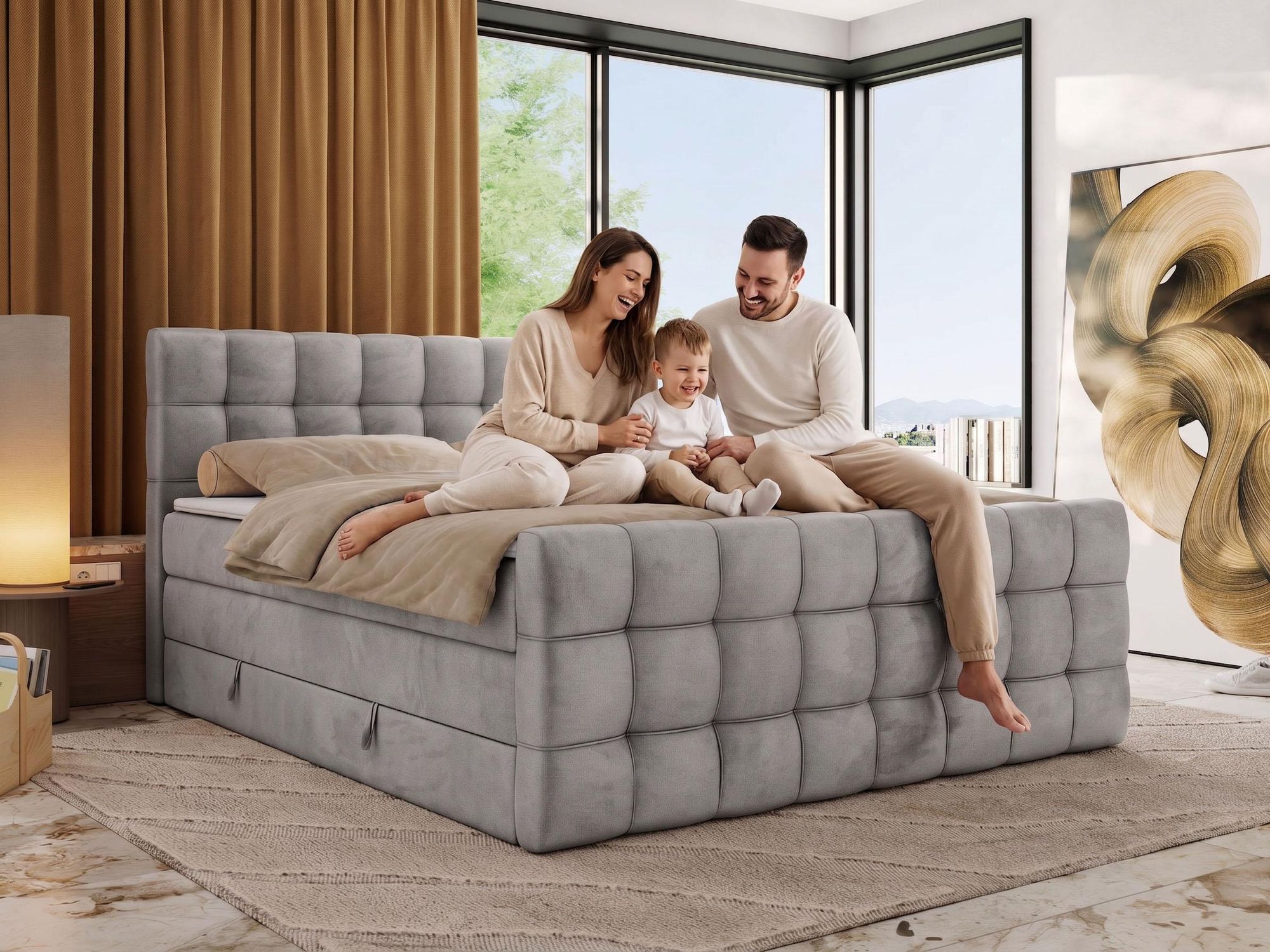 Familie sitzt auf einem grauen Polsterbett im hellen Schlafzimmer.
