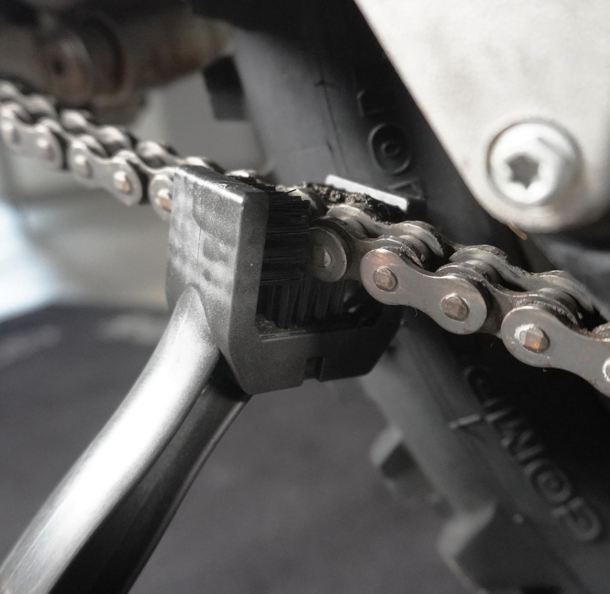 Das Bild zeigt das dreiseitige Bürstenende. Diese umschließt eine Motorradkette.
