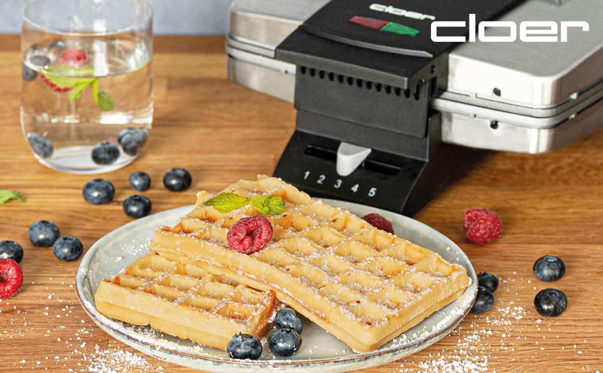 Klör Waffelautomat im Anschnitt zu sehen. 2 Belgische Waffeln aufem Teller mit Beeren verziert