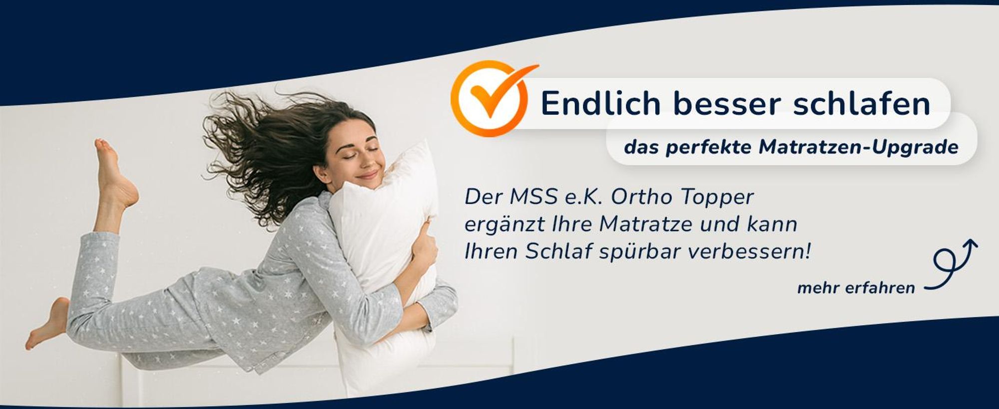 Frau liegt baeuchlings auf einem Bett und umarmt ein Kissen