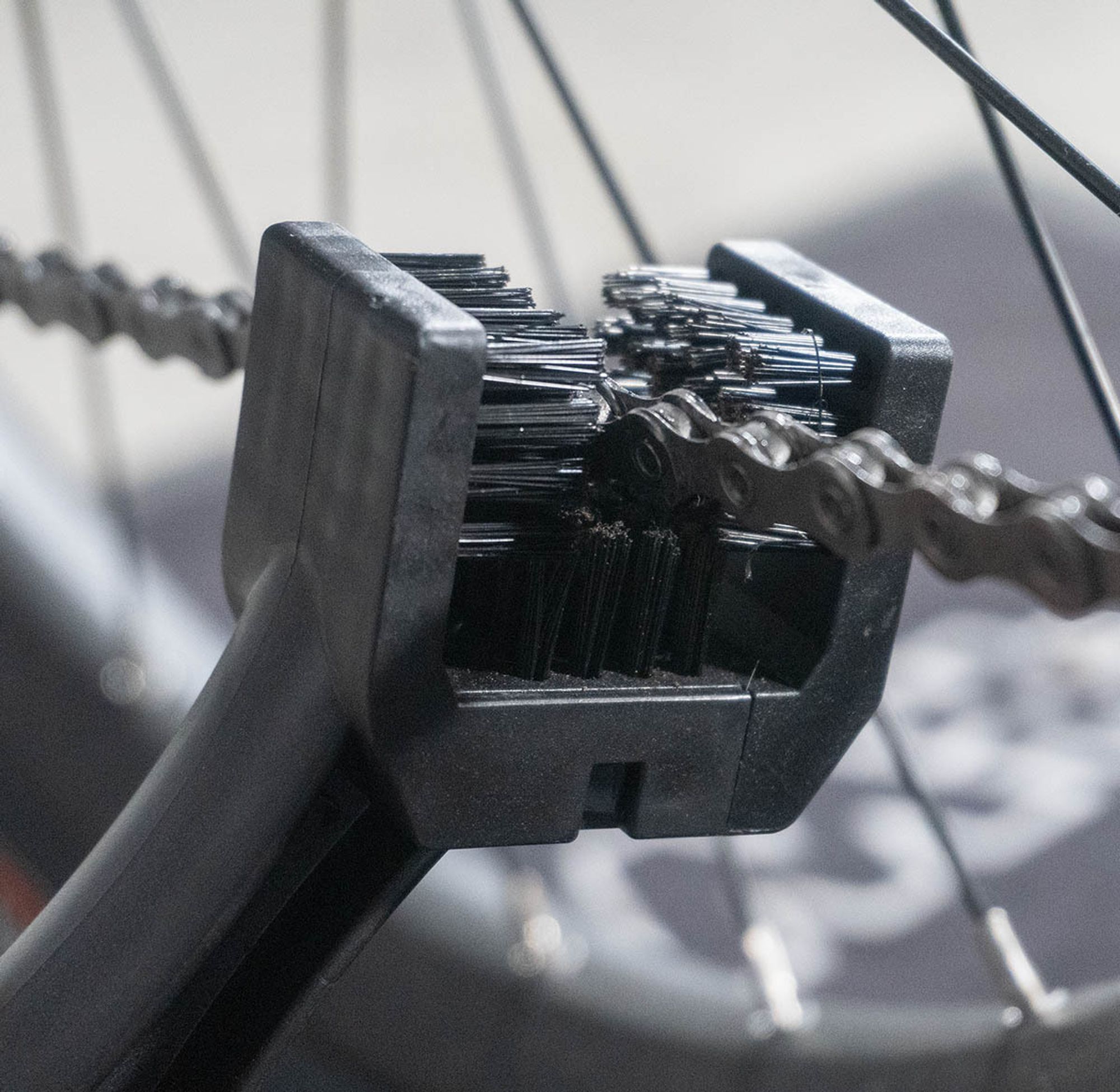 Das Bild zeigt das dreiseitige Bürstenende. Diese umschließt eine Fahrradkette. Im Hintergrund sind die Speichen des Hinterrades zu sehen.